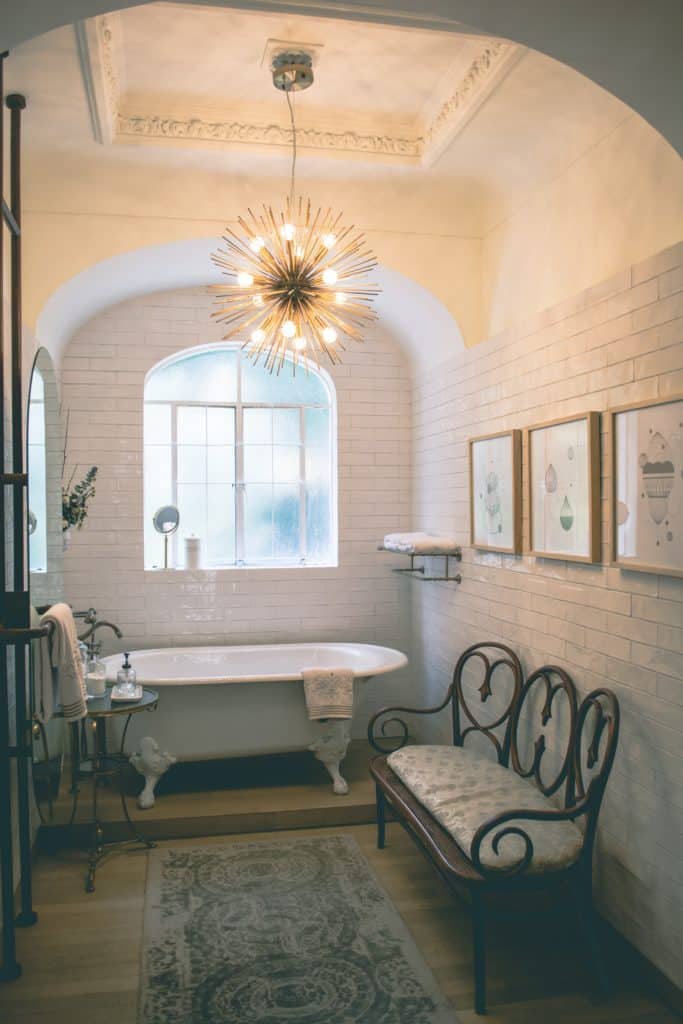 bathroom with clawfoot tub, tile walls, and spike chandelier