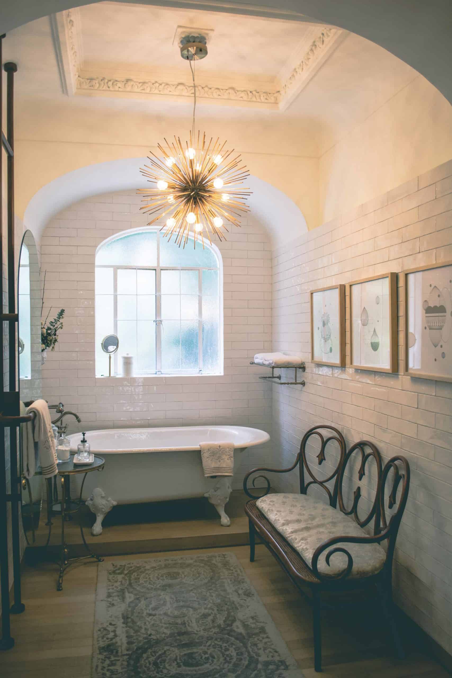 Bathroom with claw foot tub and spike chandelier with tile walls